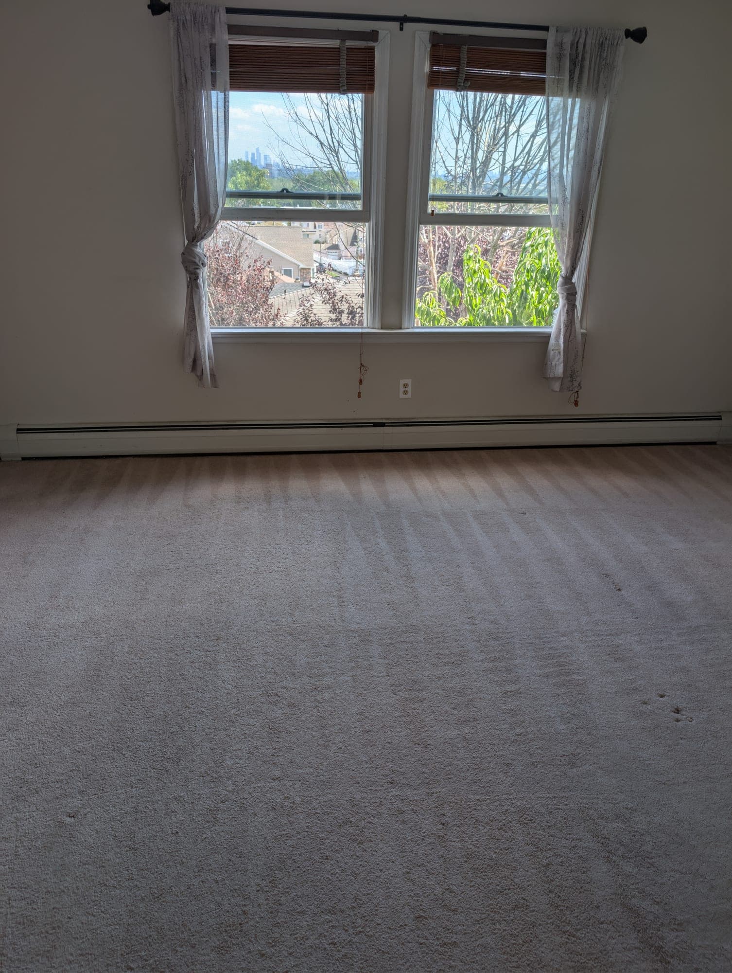 NJ apartment bedroom with cleaned beige carpet and NYC skyline visible through the window