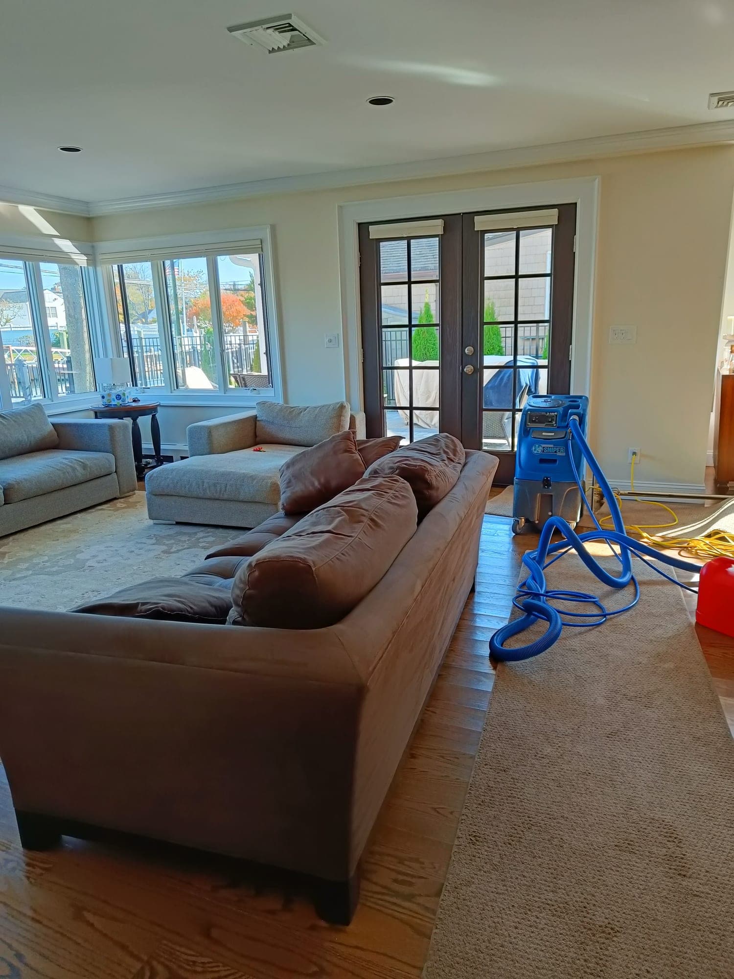 Dan's crew on a real Bergen County NJ job — brown sectional living room, blue hot-water extraction equipment in action