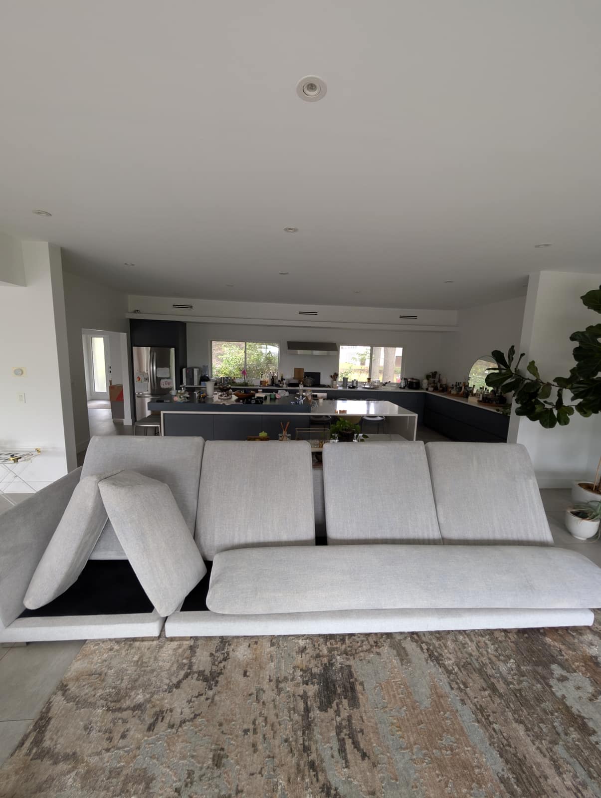 Modern open-plan NJ living room with a light gray sectional and abstract area rug over hardwood, freshly cleaned